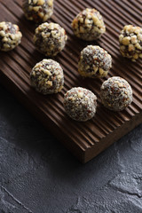 Healthy food concept. Homemade coconut energy balls on ribbed oak board on black background angle view
