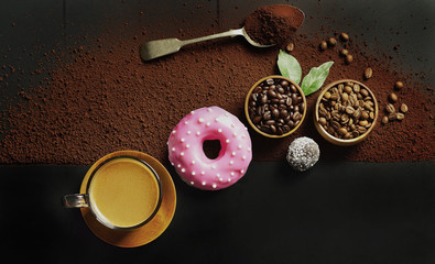 Espresso coffee and coffee beans in a wooden bowl put beside fresh donuts on a dark wooden table, top down view and flat lay horizontal.