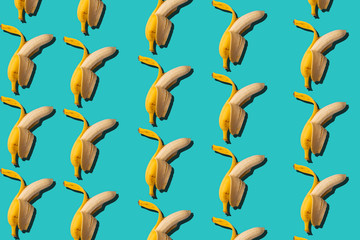 Seamless background with bananas. Abstract tropical background. Half peeled banana on a blue background.