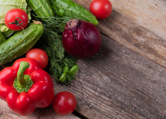 Fresh vegetables vegetables tomatoes, onions, cabbage, sweet peppers, cucumbers on a textural wooden background