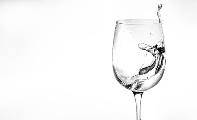 Water in a wine glass. Splash of liquid on a white background. Isolated object. Spray. Copy space for text. Selective focus.