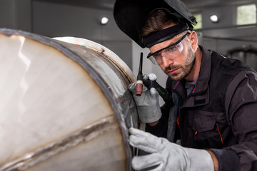 Industrial worker protective mask welding metal structure at workshop.