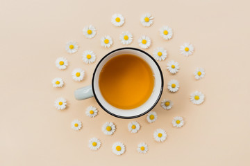 Ceramic Mug of chamomile tea with flowers on a beige background, top view with copy space for your design. Herbal medicine concept. Template or banner. Flat Lay