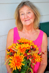 Mature female senior beauty expressions holding flowers outdoors.