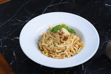 italian cuisine, noodles on a black background, served with meat, chicken, vegetables, greens, cheese, sauce, red pepper