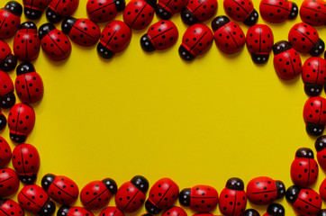 Toys frame. Wooden ladybugs frame on yellow background. Copy space. Ladybug pattern.