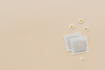 Chamomile tea bags with flowers on a beige background, top view with copy space for your design. Herbal medicine concept. Template or banner. Flat Lay