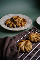 Fresh pastries, hot tasty cinnamon rolls on a green background with a burgundy dishcloth. Buns for dessert for hot drinks. Top view.