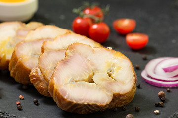 Smoked Sevryuga or sturgeon on a black slate Board on a black table. Smoked fish Sevryuga. Fish slicing