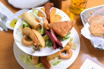 mixed snack plate with sausage, sausage, greens, salad, onion rings