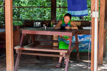 A young girl with a tablet at a campsite makes notes. Wooden table and benches. Comfortable camping. Horizontal.