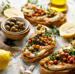 Hummus open faced sandwich with addition chopped fresh parsley, olive oil and chickpeas closeup view. 