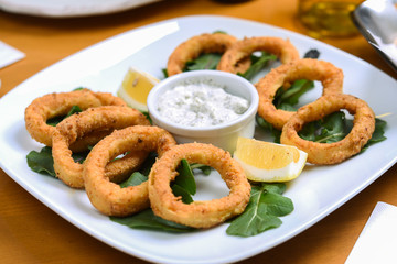 snack onion rings and sauce on pieces of greens