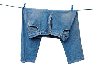 Wet wrinkled blue shabby jeans hanging on a wire on two clothespins for drying outdoors. Washing clothes, things at home in everyday life. Close-up. Isolated object on a white background.