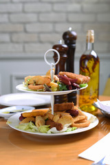 mixed snack plate with sausage, sausage, greens, salad, onion rings