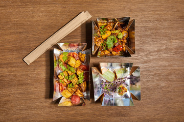 top view of takeaway boxes with prepared chinese food on wooden surface