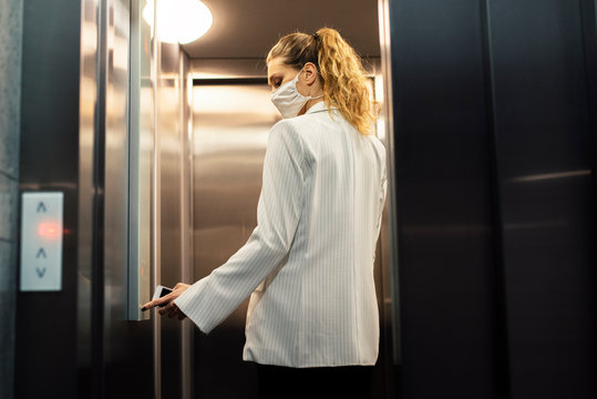 Woman wearing face mask using elevator