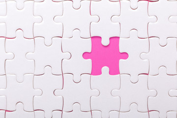 White jigsaw puzzle with with one piece missing and pink background