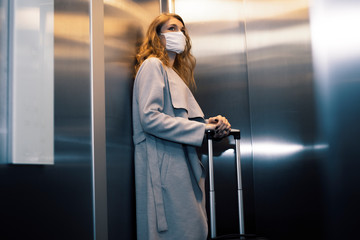 Traveler wearing protective face mask is using an elevator during epidemic