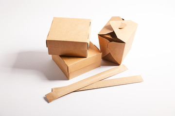 chopsticks in paper packaging near takeaway boxes with chinese food on white
