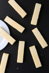 Tasty wafer sticks on yellow background, flat lay. Sweet food