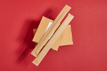 top view of chopsticks in paper packaging on carton boxes with chinese food on red