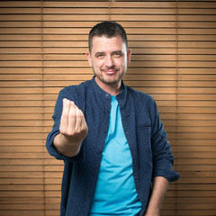 Young man wearing a blue outfit. Doing money gesture.