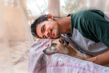 hombre joven y perro domestico, apoyan sus cabezas sobre el respaldo de un sillon en el jardin y...