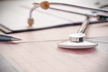 stethoscope with pen glasses, magnifier and cardiogram and other medicine equipment lay on a table