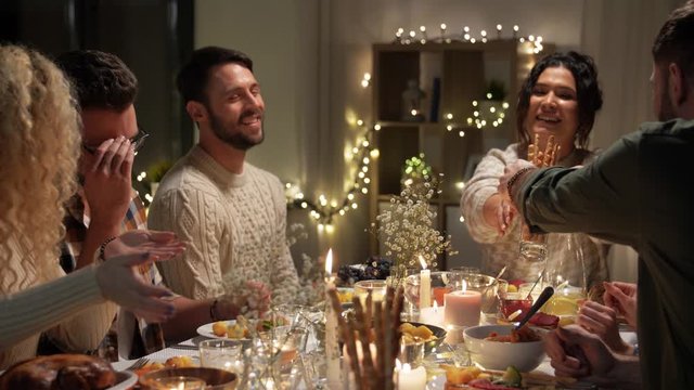 holidays, celebration and people concept - happy smiling friends having christmas dinner and sharing food at home in evening