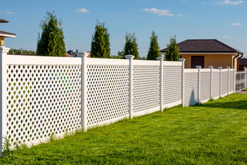White vinyl fence in a cottage village. Several panels are connected by columns. Fencing of private...