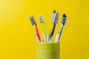 four toothbrushes in a green glass