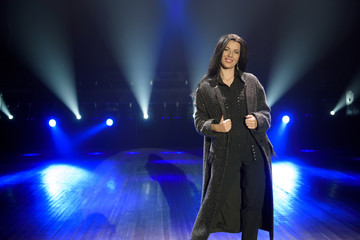Female artist on the stage on dark background, smoke, blue spotlights