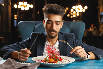 A young guy sits at a table and is going to eat