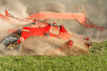 Agricultural equipment shreds the plowed land. A crawler tractor pulls a harrow to loosen the soil...