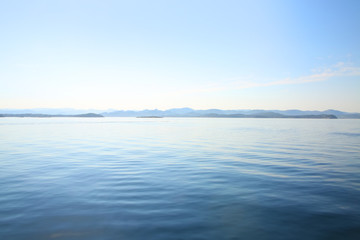 Obraz premium View over the calm ocean looking towards the horizon with pale pastel shades of blue, turquoise & white, off the coast of Stavanger, Rogaland county, Norway.