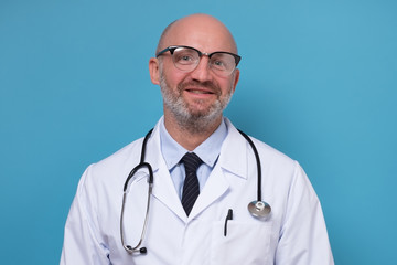 Fototapeta premium Smiling mature doctor in white coat and stethoscope isolated on blue background