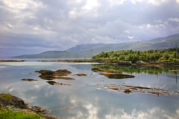 Beautiful landscape along with waters edge, with a village & church & mountains in the background, Saltstraumen, Municipality of Bodo, Nordland county, Norway.