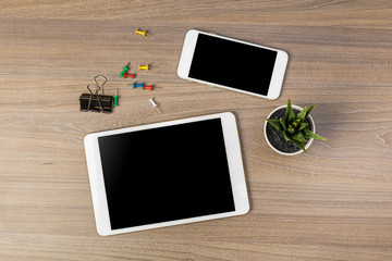 White digital tablet and mobile phone on an office working dark wooden table.