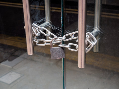 A retail shop glass front doors, padlocked and chained shut. For security and safety.