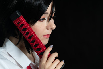 Girl with a katana in a school uniform. Cosplay. On a black background studio shooting. portrait...
