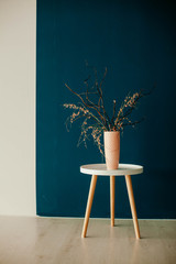 vase with dry grass on the table on a blue background