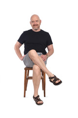 Bald man with sandals t-shirt and shorts sitting on white background