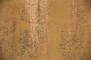 background of an ocher shade iron wall with cracked paint. Ocher wall with cracks