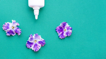 Flower allergy concept. White spray can with violet flowers on a green background. Creative flat lay, copy space