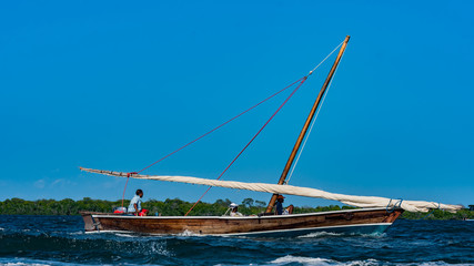 A traditional Arab dhow with a sail down but being propelled with a motor engine in Lamu Island