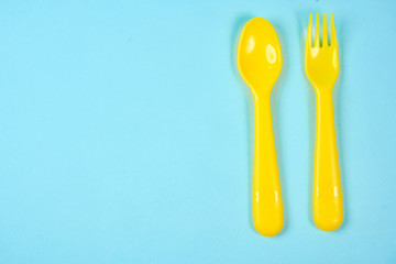Multicolored plastic dishes on a blue background. The concept of environmental pollution by plastic, ecolog place for text, flat lay