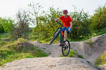 Fototapeta na wymiar Professional cyclist in a bright T-shirt performs a jump.