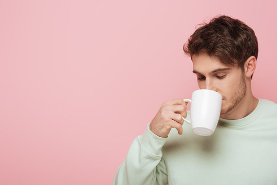 Handsome Young Man Drinking Coffee From White Cup Isolated On Pink