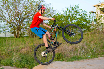 Fototapeta na wymiar Professional cyclist in a bright T-shirt performs a jump.